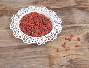Dried goji berries in white bowl on wooden background
