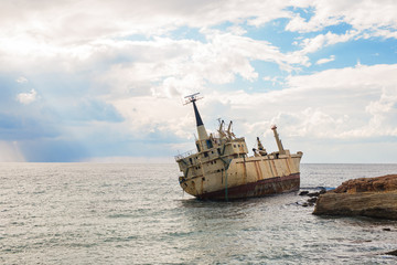 Abandoned broken ship-wreck beached on rocky sea shore.