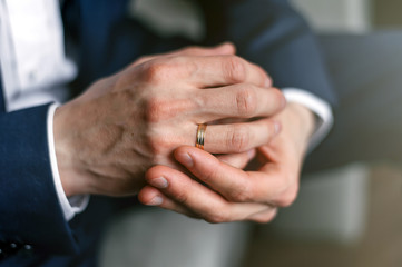 Hands of the groom with an engagement ring.