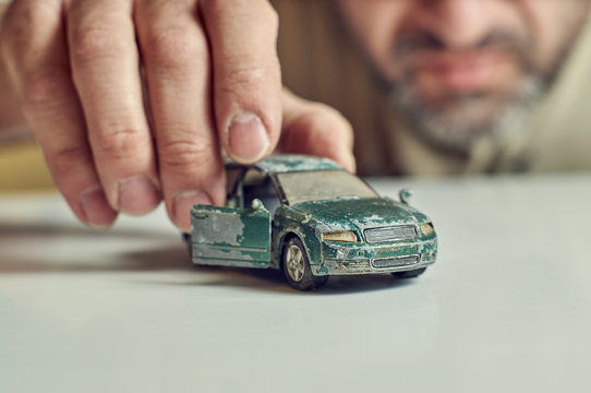 Middle-aged Man Plays With Shabby Toy Car