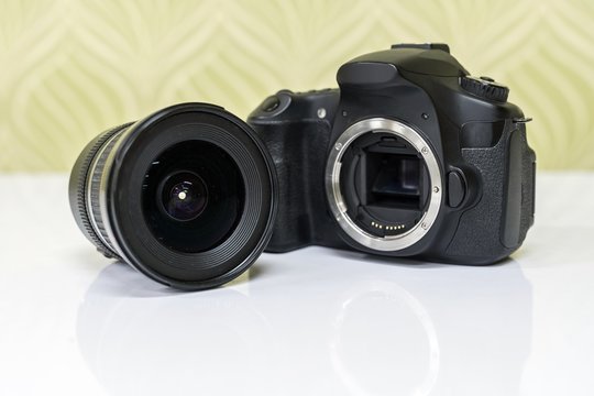 Front view of dslr camera with lens on white table. 
Close up of electronic circuit, rear glass and mount with copyspace in foreground.