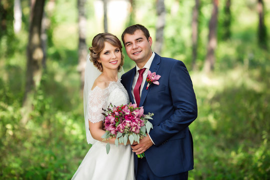 Portrait of happy bride and groom in park at wedding day