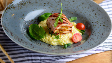 Juicy chicken roll with risotto, cherry tomatoes and greenery on a plate served for a dinner in a restaurant. Tasty food concept.