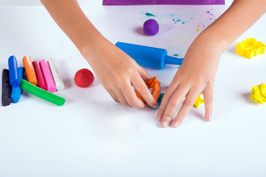 Little hand of kid learn to play colorful dough on white table