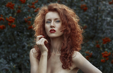 Portrait of a beautiful red-haired girl in the nature. Naked shoulders