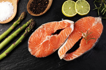 Fresh raw salmon fish steaks with fresh herbs on stone background