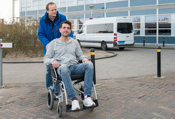 Father Pushing Son On Wheelchair With Van In Background