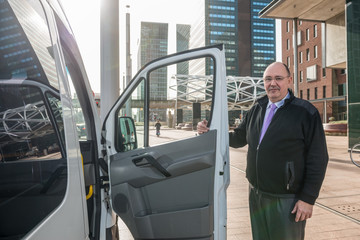 Confident Taxi Driver Standing By Van At Airport