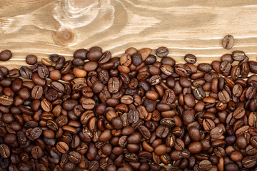 Roasted coffee beans scattered on wooden background.