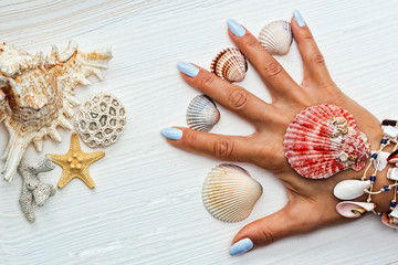 Female hand with manicure and sea shells between fingers