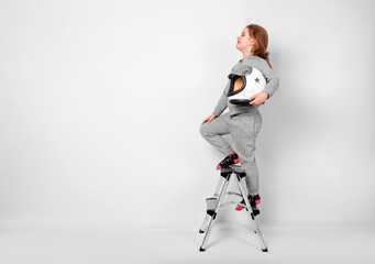 Happy child girl dressed in an astronaut costume standing on stepladder