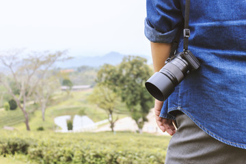 Close-up shot of man hand holding camera with  soft-focus in the background. over light and old film colors tone