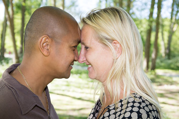 blonde woman and a man of Indian origin make a kiss