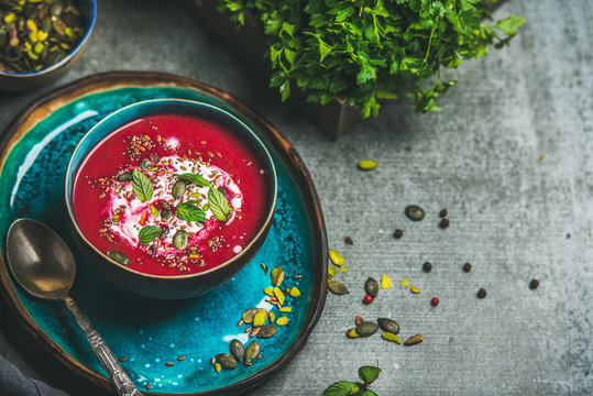 Spring detox beetroot soup with mint, chia, flax and pumpkin seeds on bright blue ceramic plate over grey concrete background, copy space. Dieting, clean eating, weight loss, vegetarian food concept