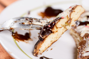 Slice of american pancake topped with chocolate cream and sprinkles on the fork closeup macro