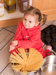 Cute little girl at kitchen cooking spaghettu