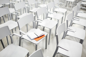 Open notebook with empty pages on white plastic chair