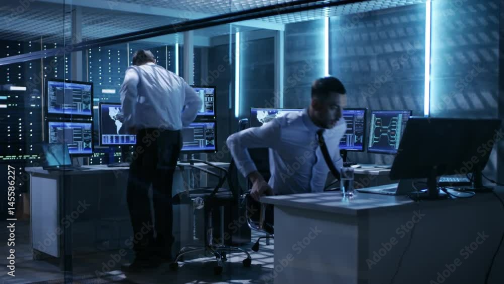 Poster Two Technical Engineers Take Their Places at Mission Control Room. Monitoring Room Has Multiple Computers and it's Own Data Center.  Shot on RED EPIC-W 8K Helium Cinema Camera.