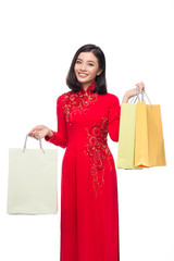 Charming Vietnamese Woman in Red Ao Dai Traditional Dress holding Shopping Bags.