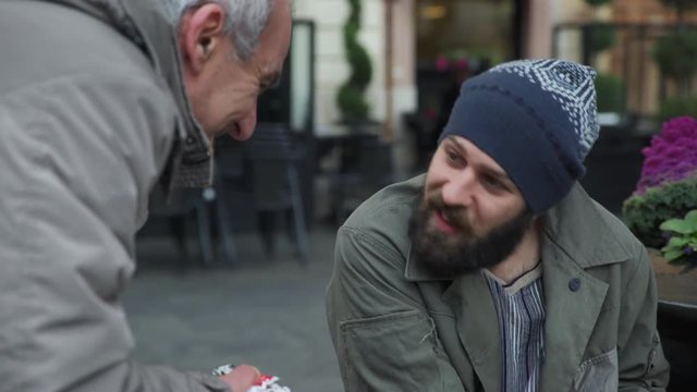 Generous man brings breakfast to a homeless caressing his face