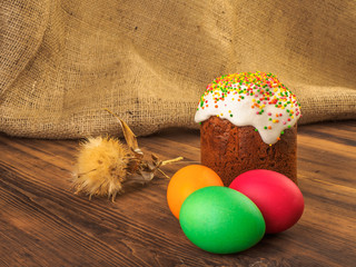 Easter cake and easter colored egg with dry flower. Russian and Ukrainian, orthodox, slavic traditional Easter kulich on rural background from old wood and burlap. Selective focus.