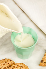 Milk poured into glass, with chocolate chips cookies