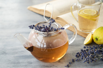 Lavender tea in a glass teapot with book in the background 
