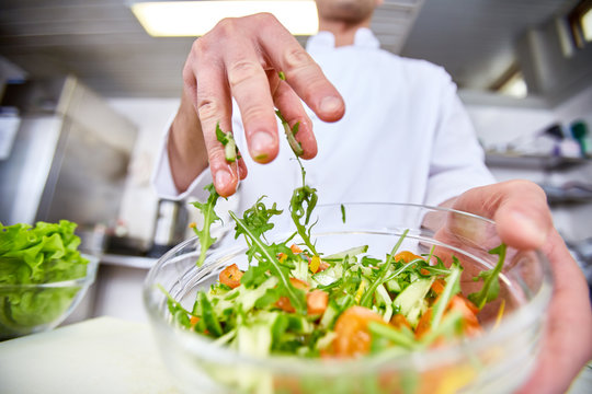 Professional chef mixing salad ingredients in bowl