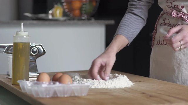 Woman hands put eggs in the flour