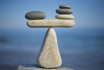 Balance of stones. To weight pros and cons. Balancing stones on the top of boulder. Close up. Balance of stones on a blue sky background with a copy space. Scales. Stones balance, sustainability.