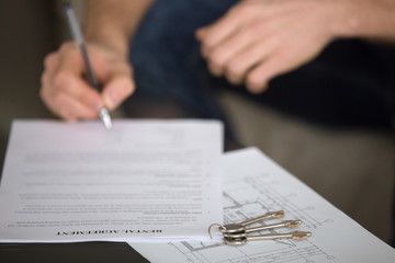 Close up of male tenant signing rental agreement, renter with a pen putting signature, focus on...