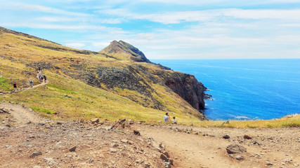 Fototapeta na wymiar trekking to Sao Lourenco. Amazing cliff view panorama with tourists sitting on the edge. Madeira island, Portugal