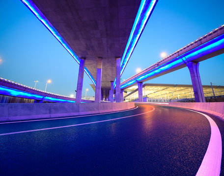 Fototapeta Empty road floor with city viaduct bridge of neon lights night