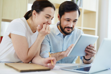Obraz premium Portrait of smiling man and young woman using modern digital devices at desk
