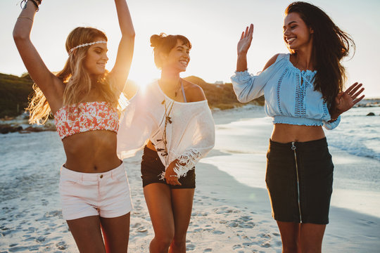 Female friends dancing together at the beach