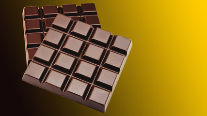 Two dark, bitter chocolate bar, on golden gradient background