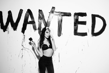 sexy painter woman with wanted text on wall hold paintbrush