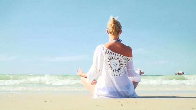 junge, blonde Frau macht Yoga am Strand