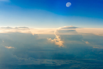 The colorful sky above the clouds with half moon airplane traveling in the summer