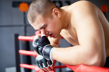 Side view portrait of sweaty exhausted shirtless boxer resting