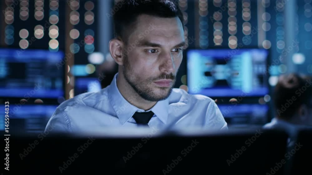 Aufkleber close-up of a professional technical controller sitting at his desk with multiple displays before hi