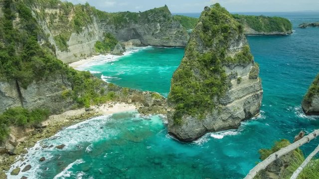 Gorgeous view to rolling waves, to the cliffs and sandy beach on the bottom with clear transparent ocean water in Nusa Penida, North Coast, Bali, Indonesia