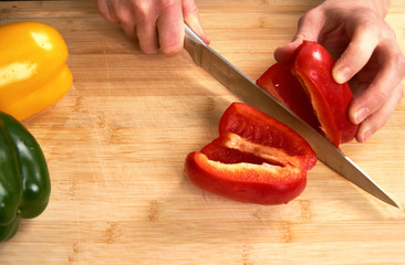 Man's hands cutting paprika in the kitchen, preparing a meal for lunch. High angle view.