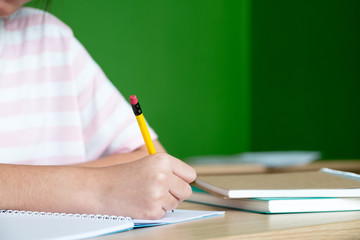 Young teenager girl writing on notebook homework at library in school,Education concept