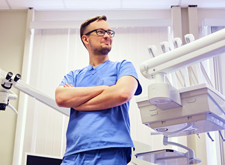 Dentist in a room with medical equipment on background.