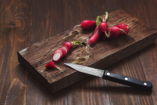 radishes on a wooden cutting Board on a rustic wooden table.