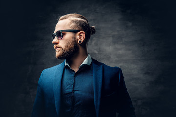 Stylish bearded male in sunglasses over dark grey background.