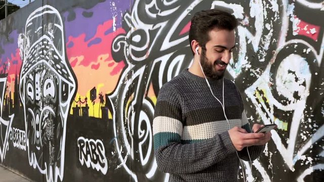 Young attractive and smiling man walking on the street chatting with cellphone