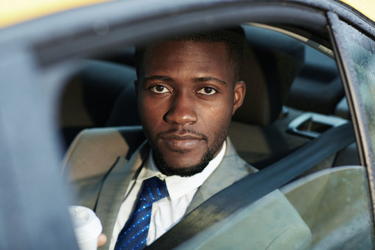 Businessman sitting in taxi cab and looking at camera