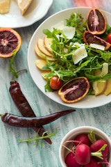Fresh spring salad with arugula, pear and orange slices and walnuts on wooden table. Selective focus